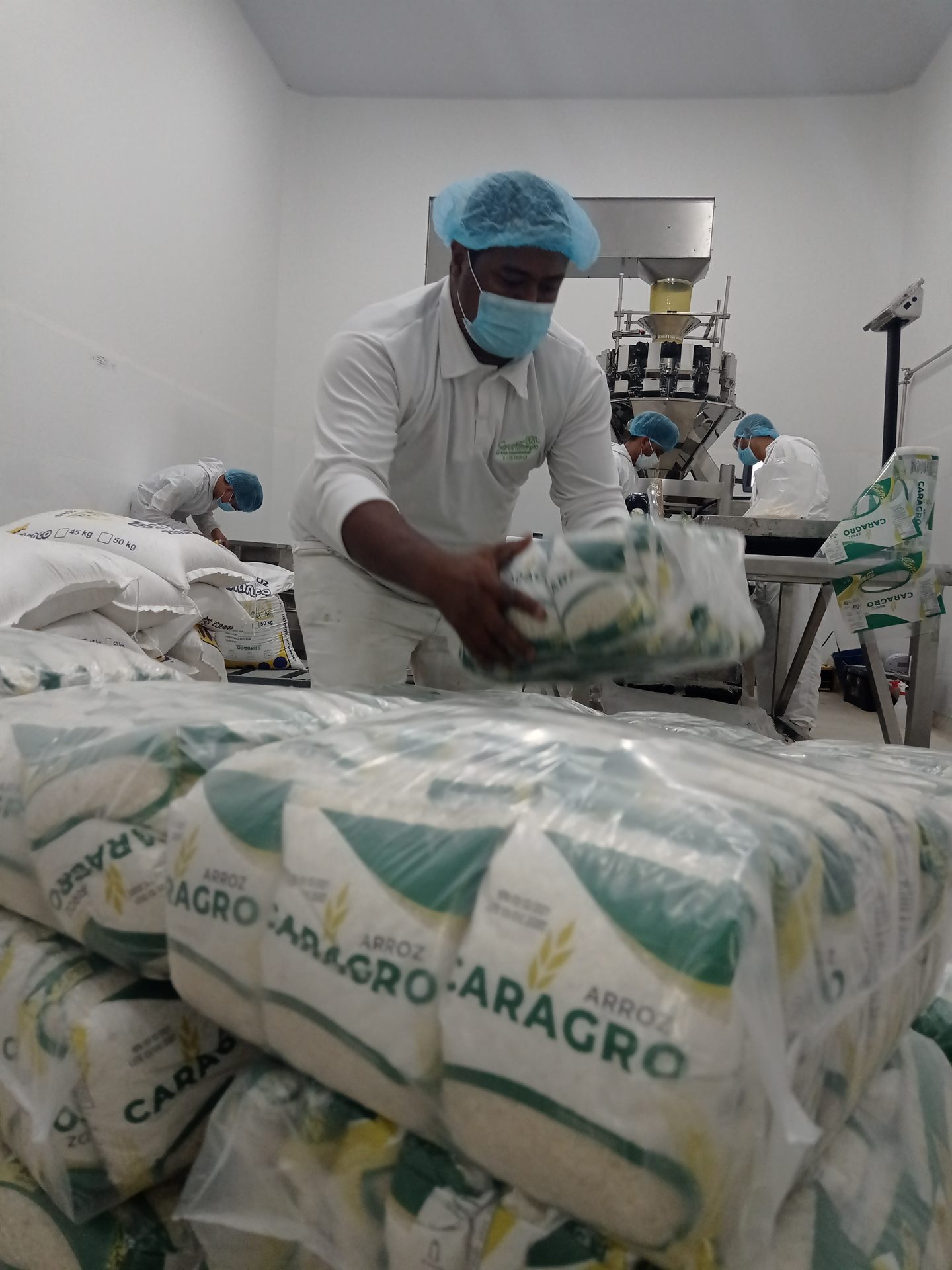 Operarios empacando arroz en planta con protocolos de inocuidad